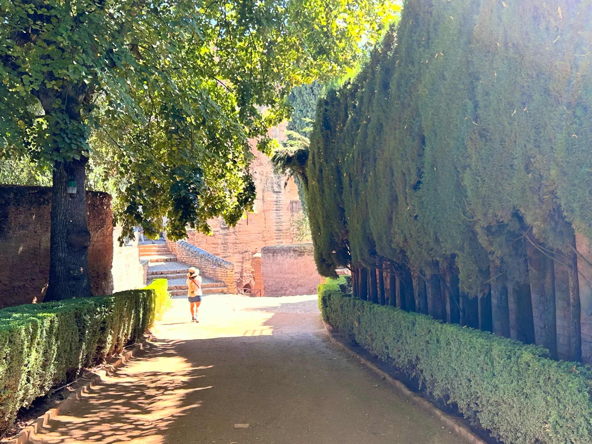 Paseo entre jardines y sombras en la Alhambra, donde la historia y la luz se encuentran en cada rincón.